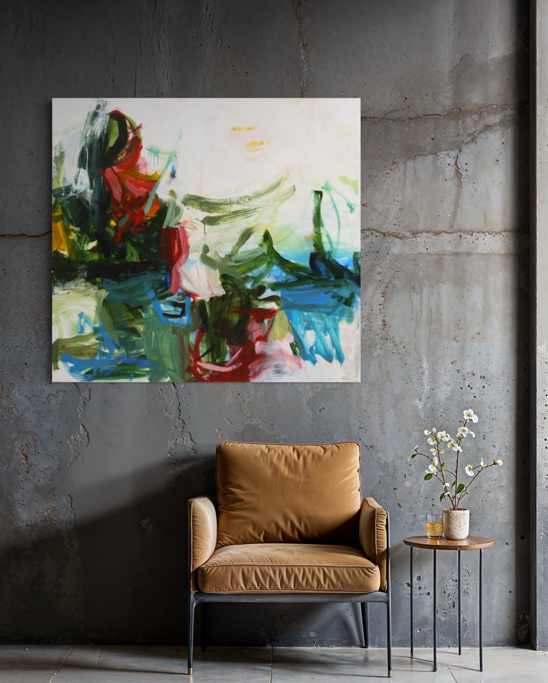 An abstract canvas painting with vibrant green, blue, red, and white brushstrokes hanging on a textured dark gray concrete wall above a mustard yellow armchair and a small side table with flowers.
