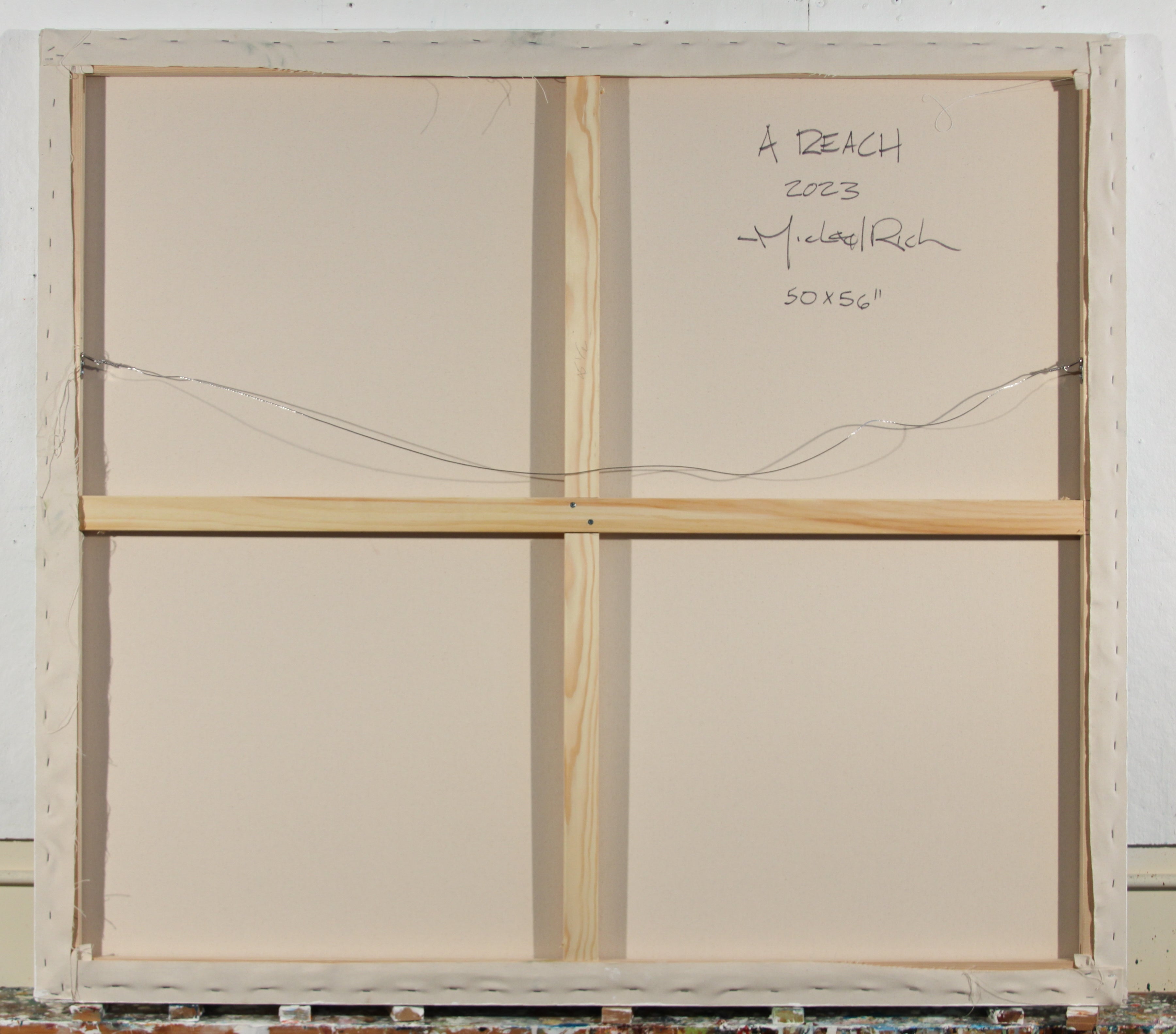 Back view of a square canvas print showing the wooden gallery frame, canvas support cords, and handwritten signature details reading 'A BEACH 2023 Michael Rick 50x50"'.