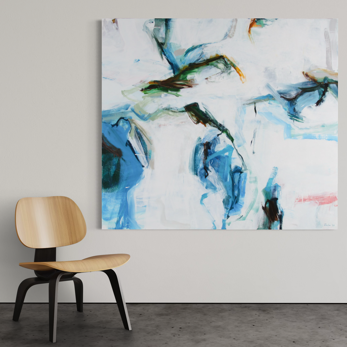 An abstract canvas painting with blue, green, black, and white brushstrokes hanging on a light gray wall above a modern wooden chair with black legs.