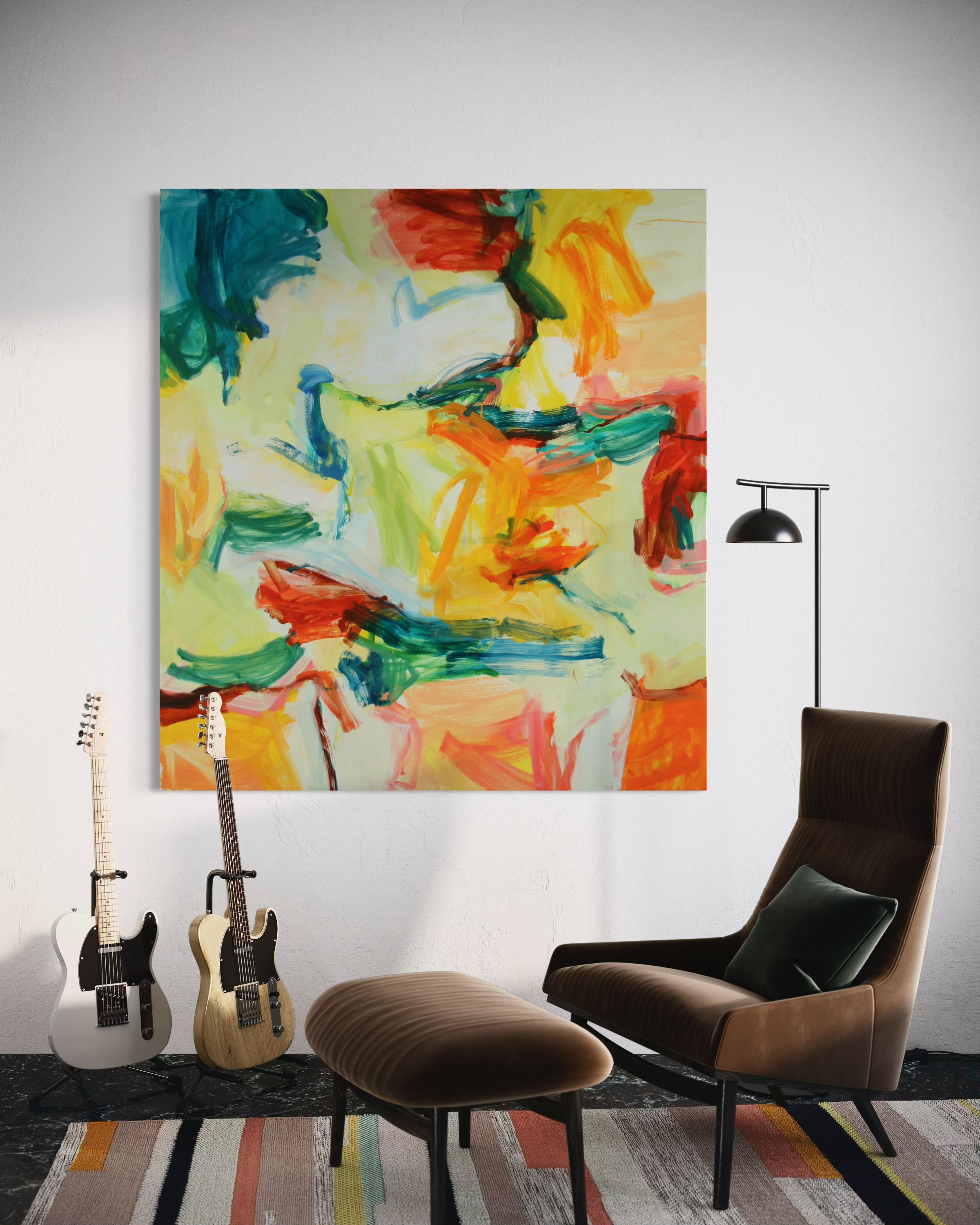 A large abstract canvas painting with vibrant brushstrokes of yellow, orange, green, blue, and red hangs on a white wall in a modern living room setting, flanked by two electric guitars, a brown armchair, and a matching ottoman.
