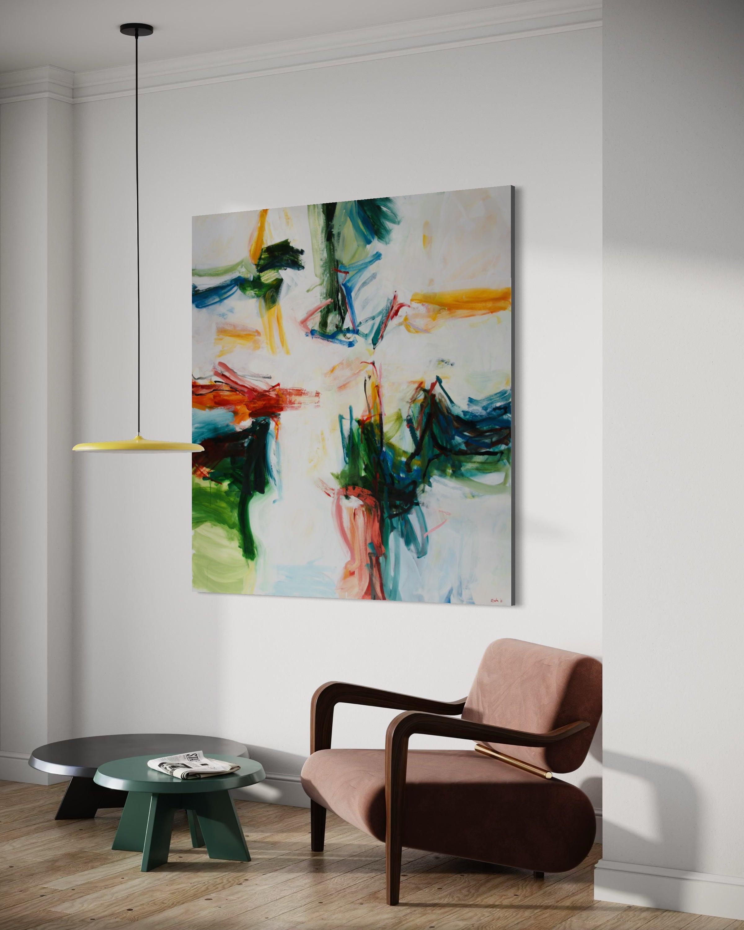 An abstract canvas wall art print with vibrant green, blue, yellow, and red brushstrokes on a white background, displayed in a modern living room setting above a brown armchair and a small green side table.