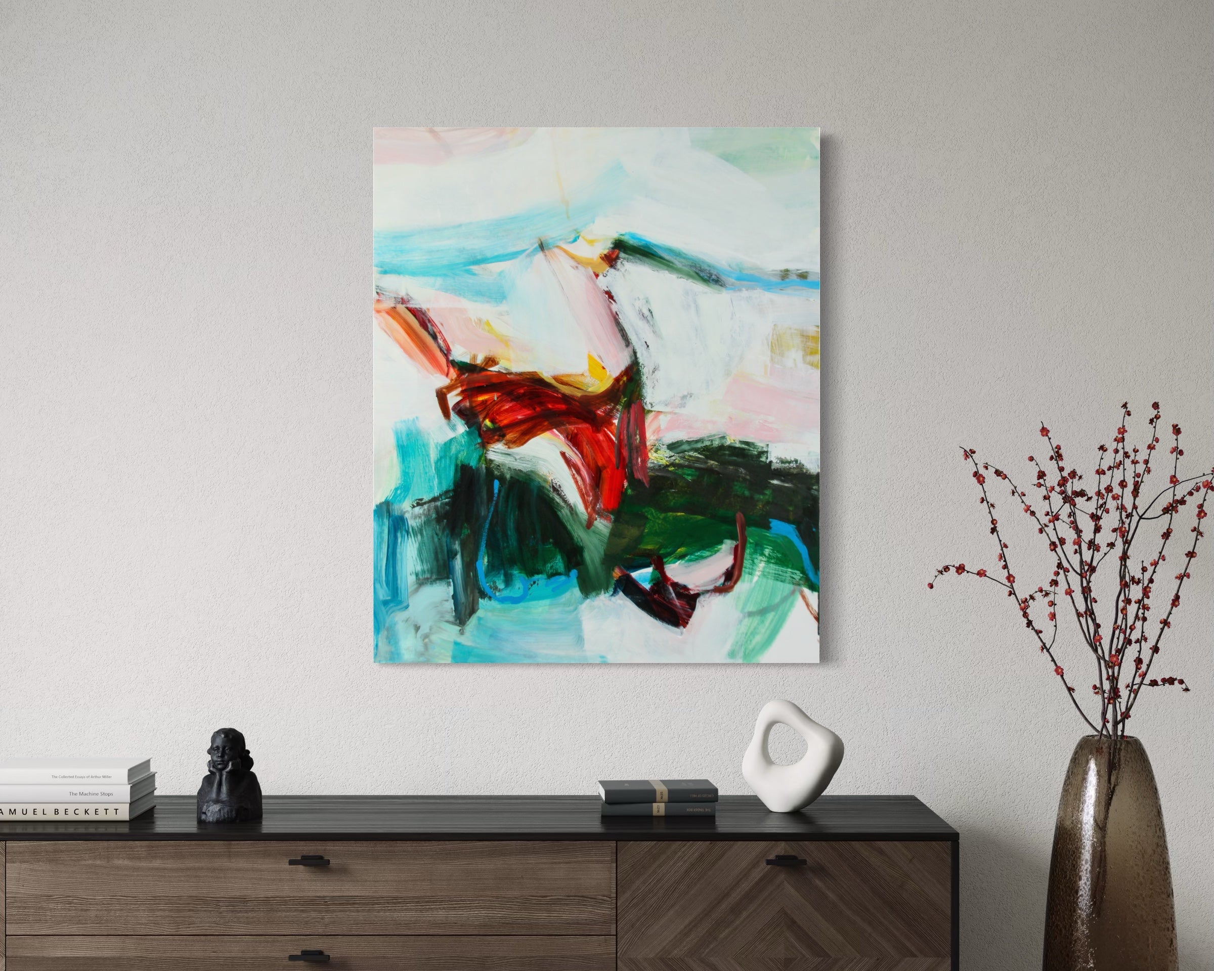 An abstract canvas painting with vibrant red, green, blue, and white brushstrokes, displayed on a light gray wall above a dark wood console table with decorative objects.