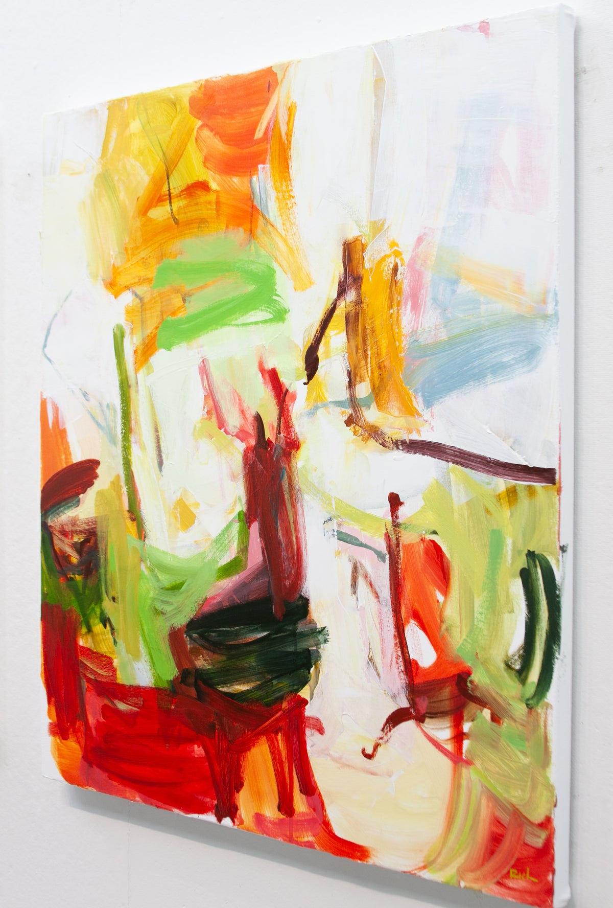 An abstract canvas painting by Michael Rich featuring expressive brushstrokes in vibrant red, yellow, green, orange, and white, shown hanging on a light gray wall.