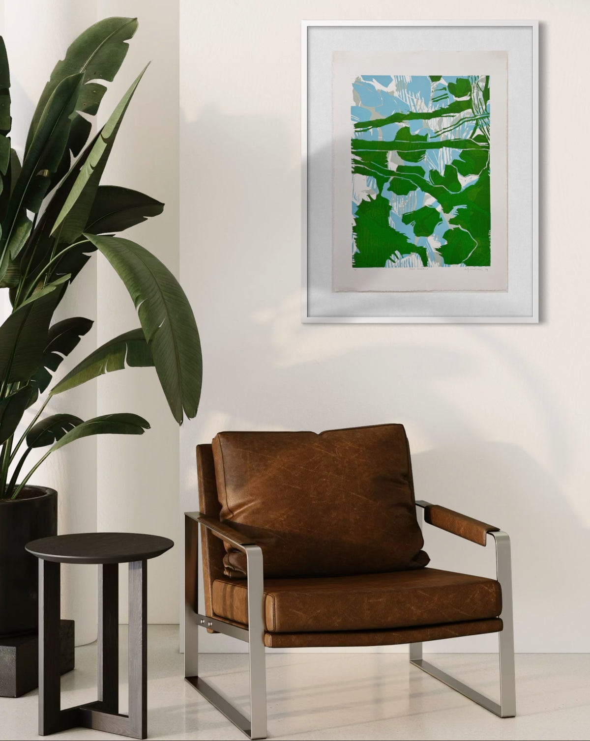 Brown leather armchair in a room with a plant and framed artwork by Michael Rich on the wall.