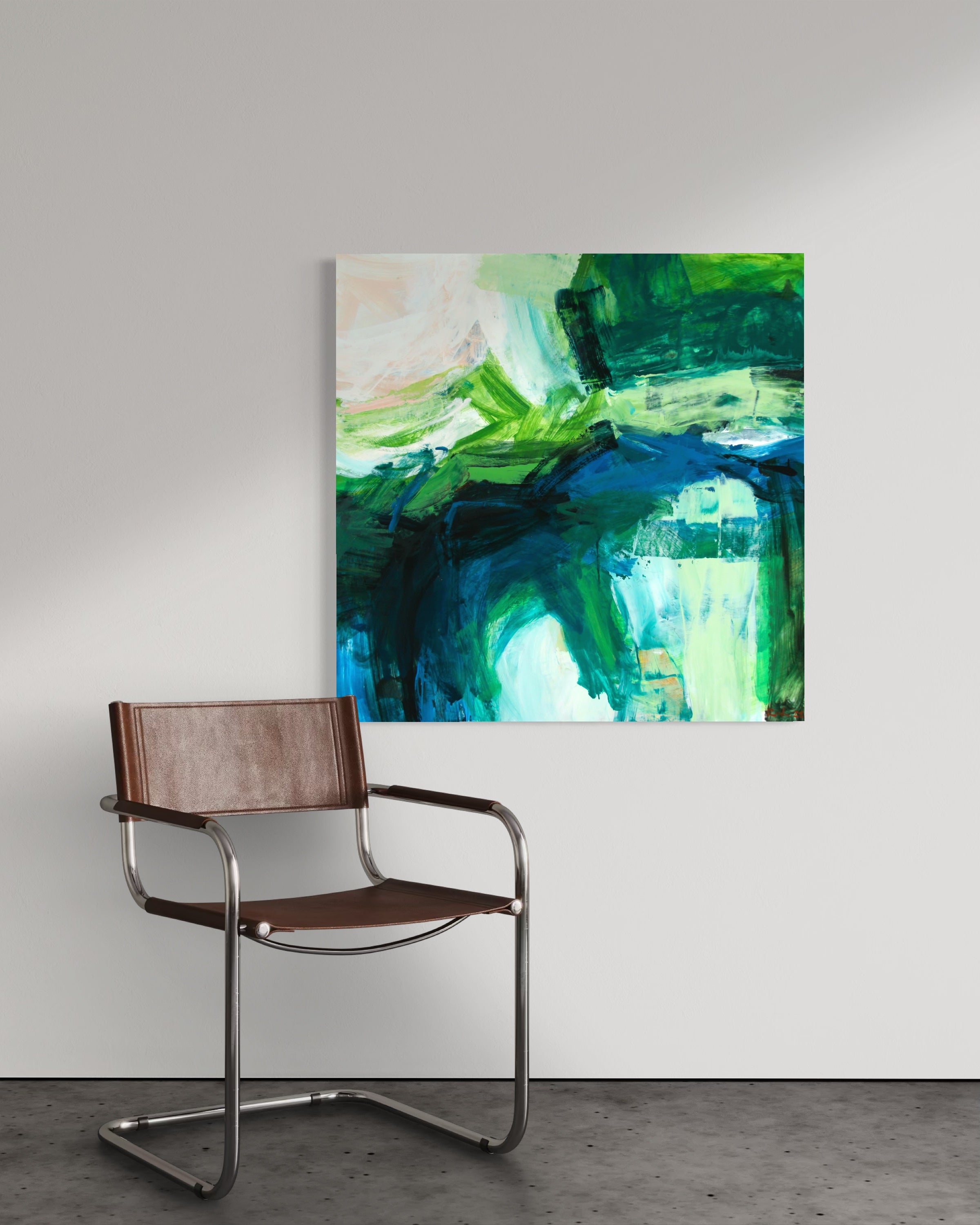 An abstract canvas painting with vibrant green, blue, and white brushstrokes, displayed on a light gray wall above a modern brown leather and chrome metal armchair.