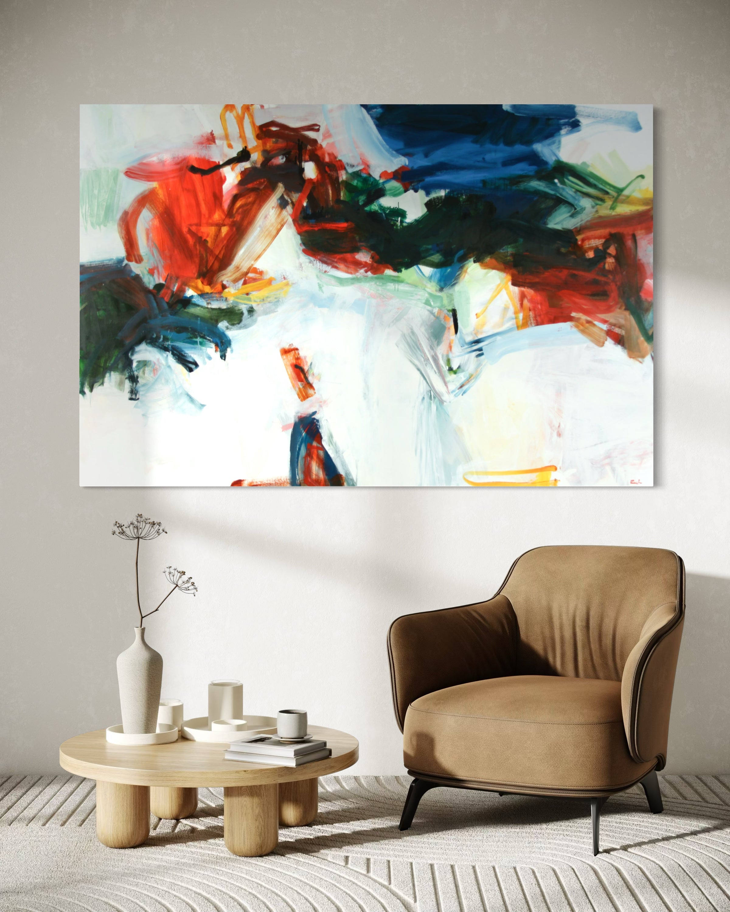 An abstract canvas wall art print featuring bold brushstrokes of red, blue, green, black, and white, displayed in a modern living room setting above a brown armchair and a small wooden side table.