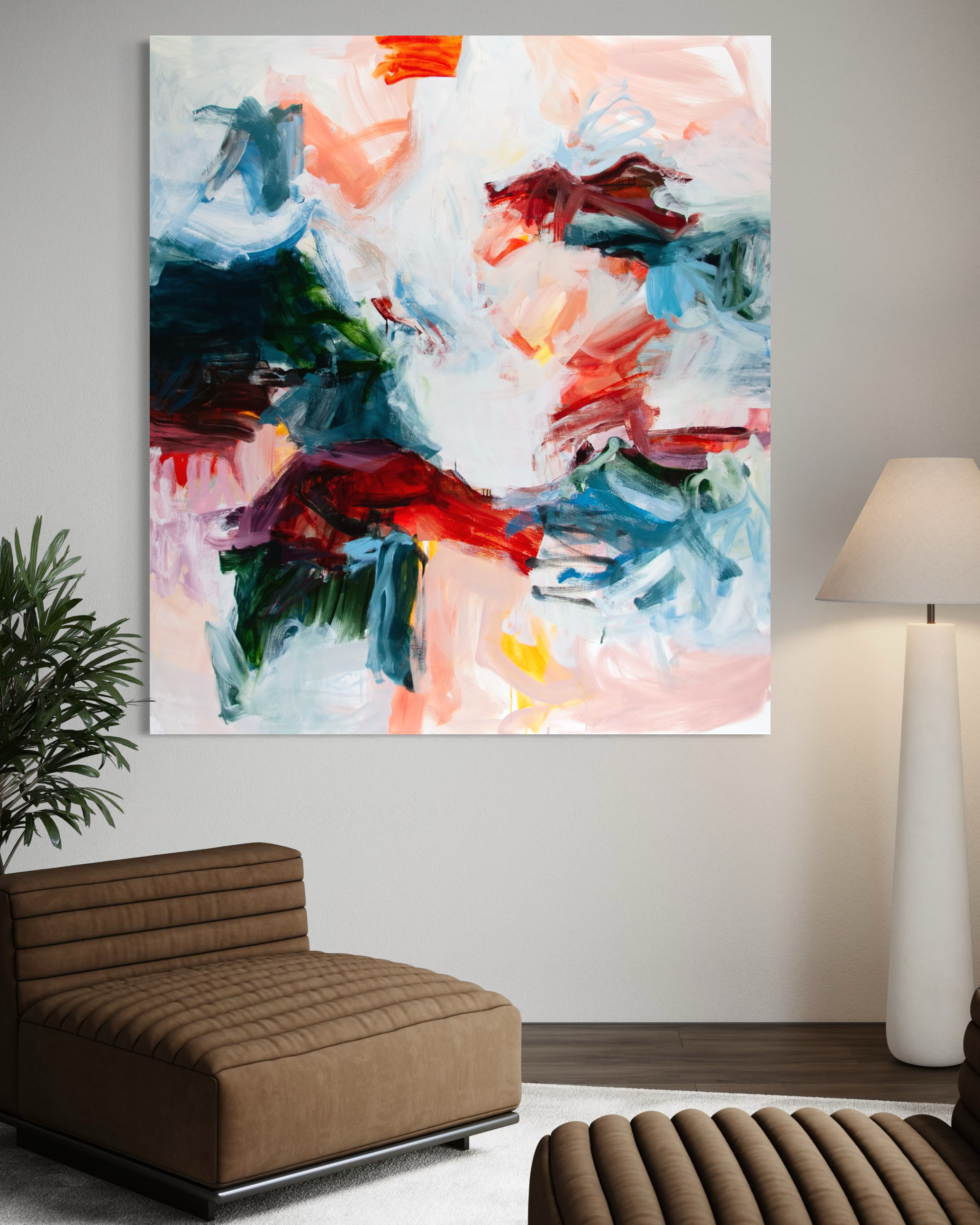 An abstract canvas painting with bold brushstrokes of white, red, blue, green, and pink, displayed on a light gray wall in a modern living room setting with a brown leather sofa and a floor lamp.