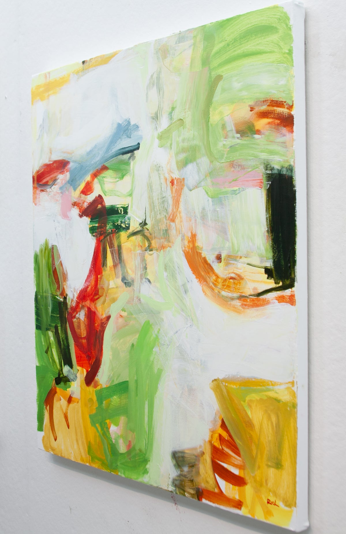 An abstract expressionist painting by Michael Rich on a white canvas, featuring expressive brushstrokes in green, yellow, red, orange, blue, and black on a white background, shown hanging on a white wall.