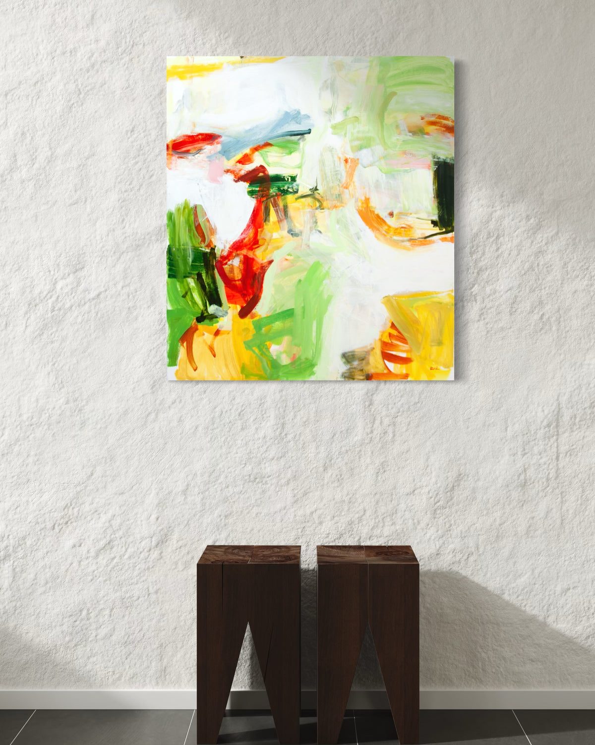 An abstract canvas painting by Michael Rich with vibrant green, yellow, red, and white brushstrokes, displayed on a textured white wall above two dark wooden side tables.