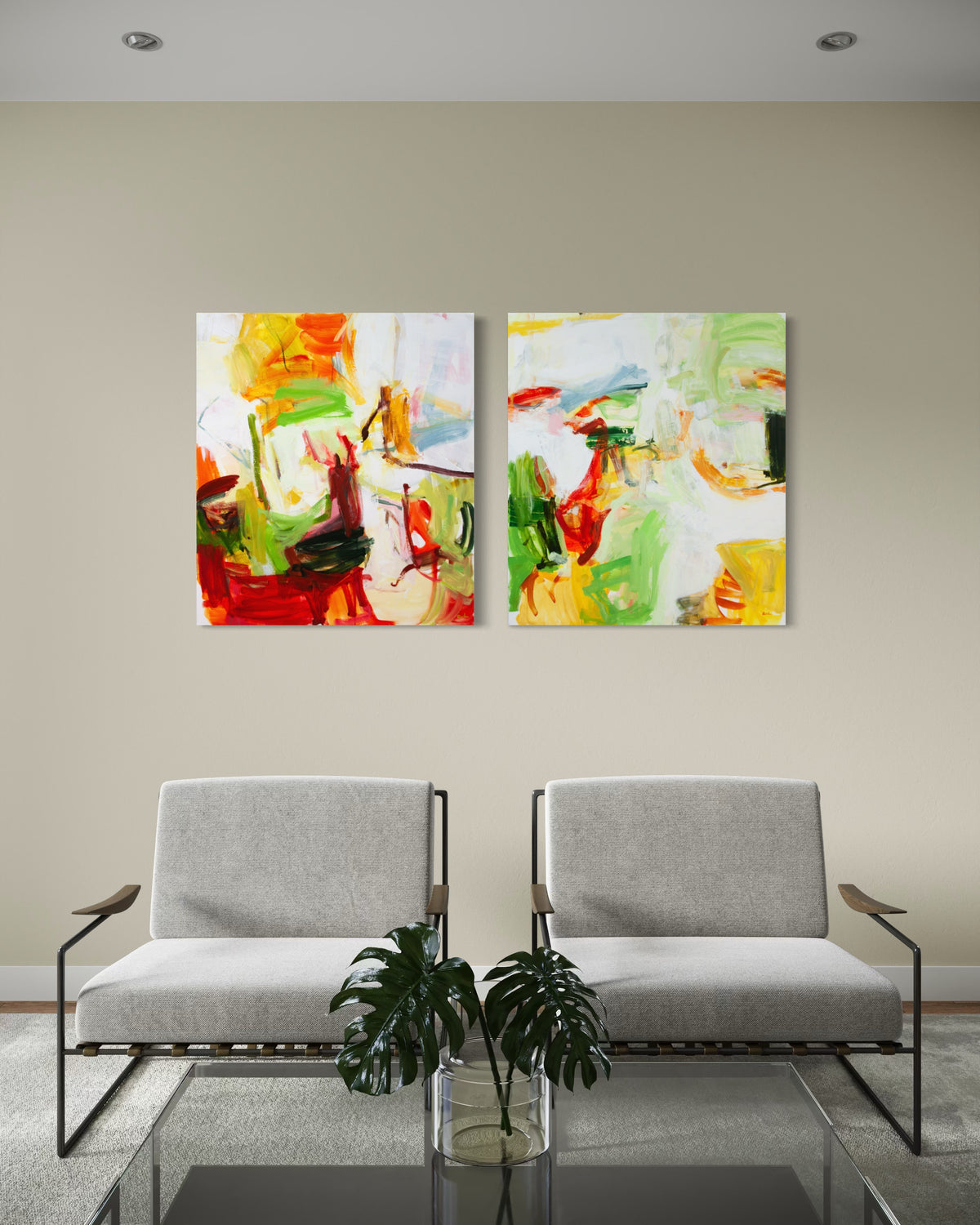 Two abstract canvases by Michael Rich with vibrant red, green, yellow, and orange brushstrokes hang side-by-side on a beige wall above a modern gray sofa in a styled living room setting.
