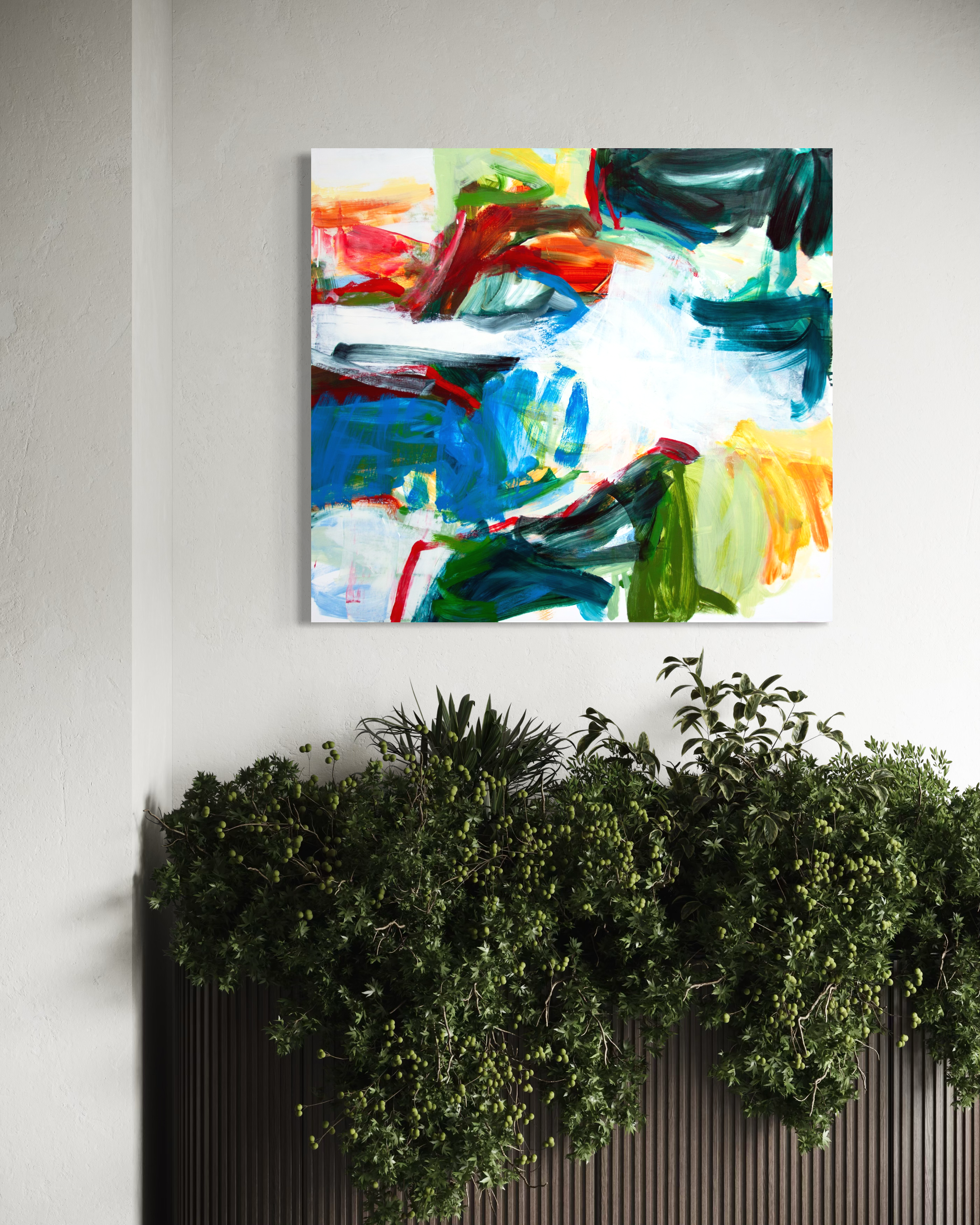 An abstract canvas painting with vibrant brushstrokes of blue, green, red, yellow, and white, displayed on a textured white wall above a dark planter filled with green foliage.