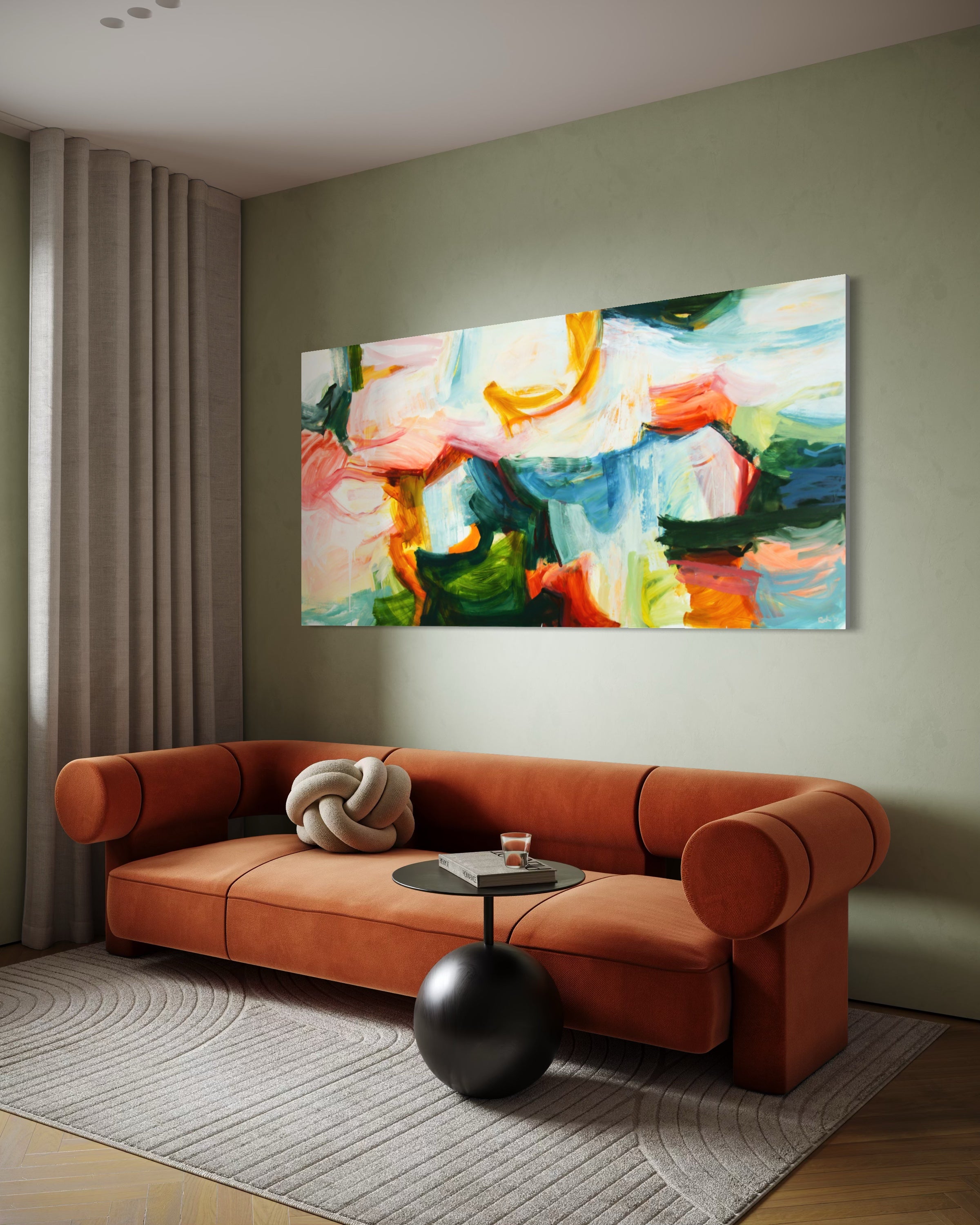 A large rectangular abstract canvas painting with vibrant green, blue, orange, pink, and white brushstrokes, displayed on a sage green wall above a rust-orange velvet sofa in a modern living room setting.