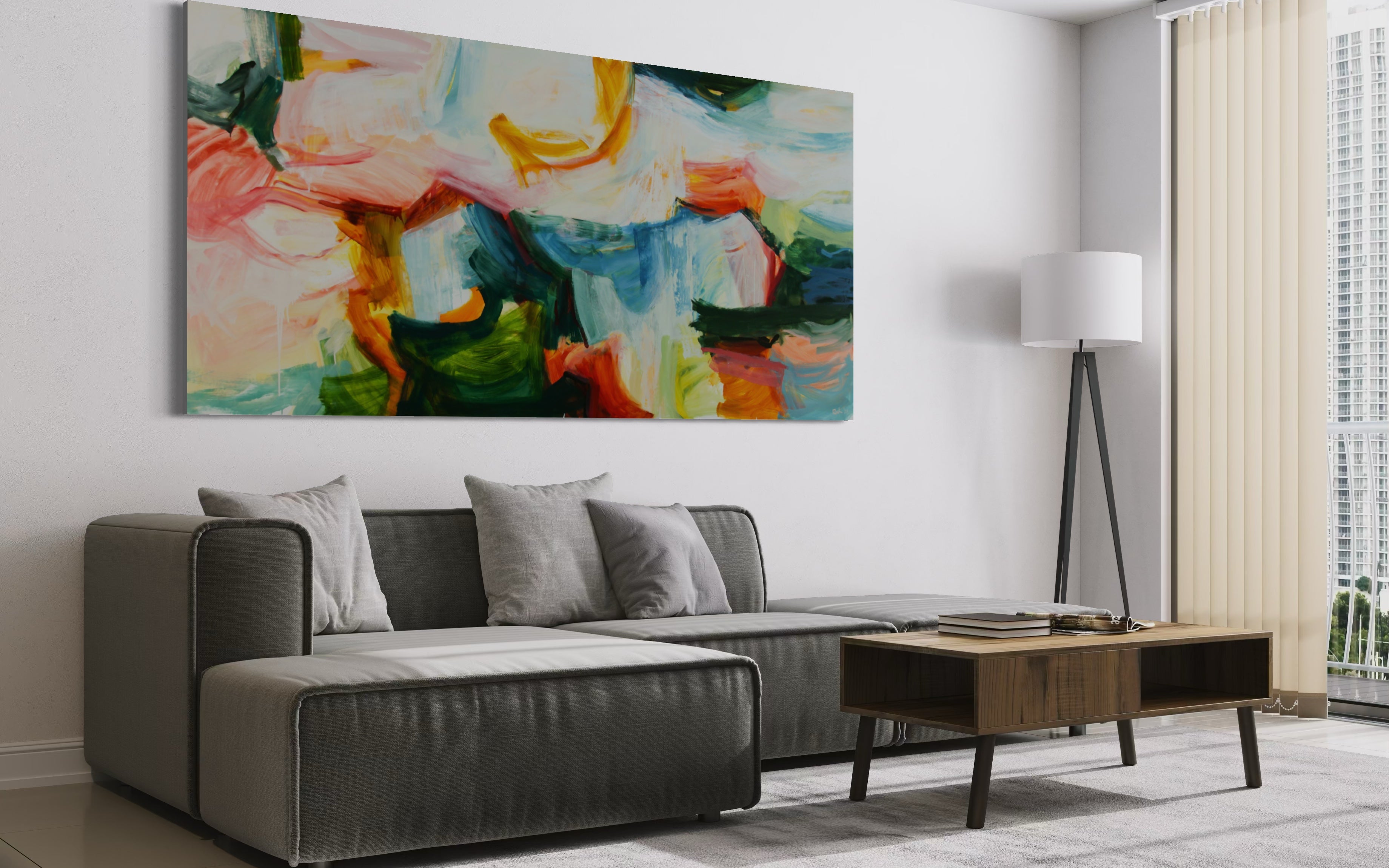 A large abstract canvas wall art print with vibrant green, blue, pink, orange, and yellow brushstrokes, displayed in a modern living room setting above a gray sectional sofa.